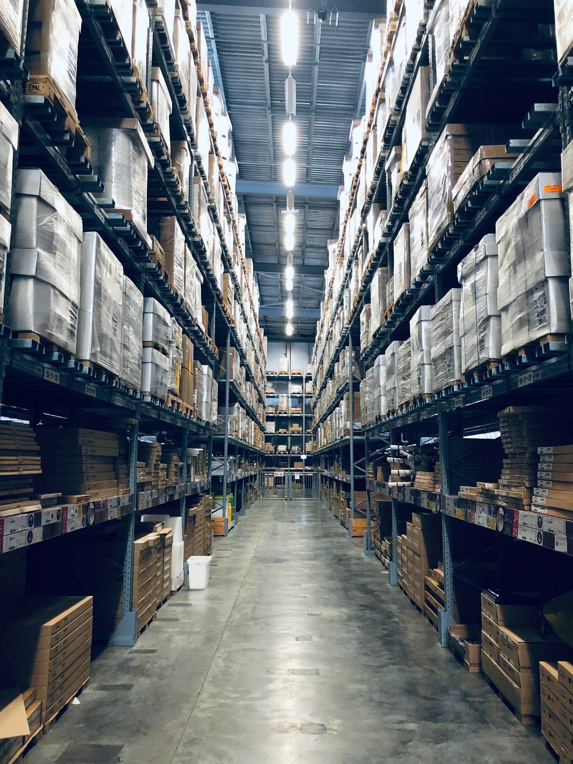 Industrial warehouse aisle stacked with palletised packaging stock